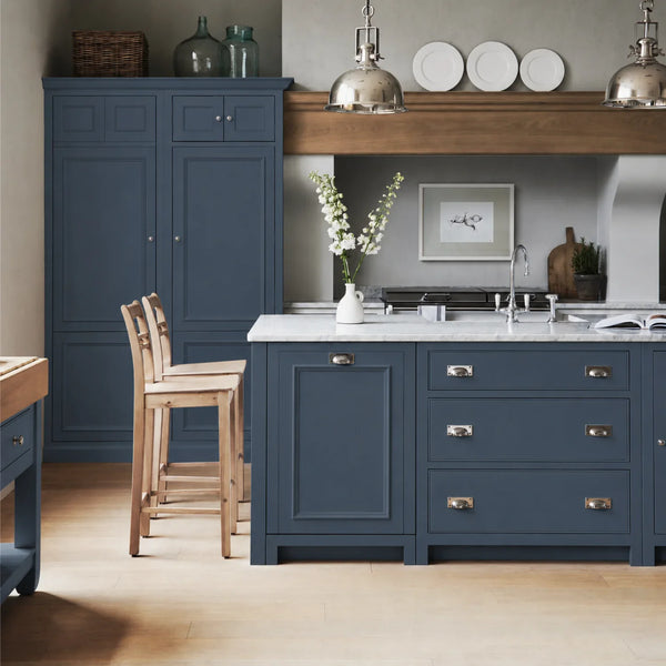 Chichester kitchen with cabinetry painted in Blakeney Blue, featuring a central island and oak bar stools.