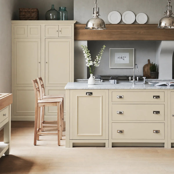 Chichester kitchen with cabinetry painted in Old Chalk cream, featuring a central island and oak bar stools.