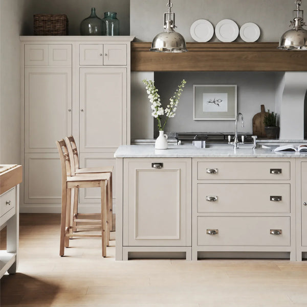 Chichester kitchen with cabinetry painted in Lily beige cream, featuring a central island and oak bar stools.