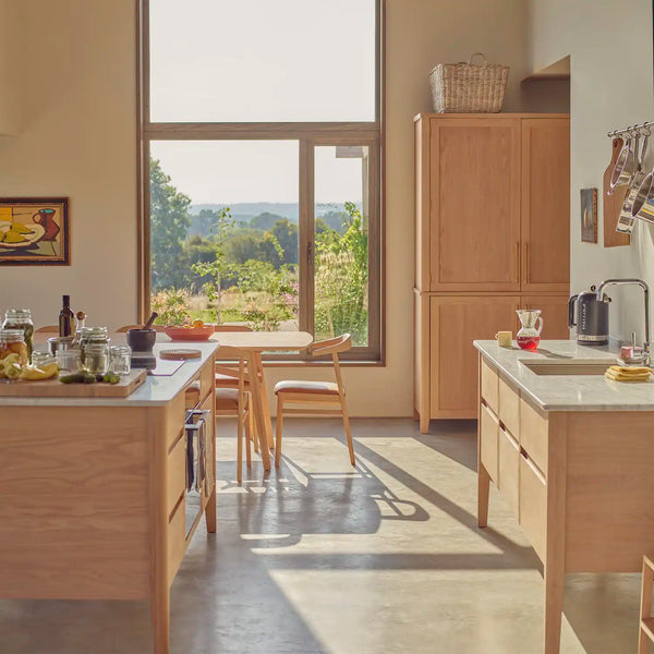 Borough kitchen with marble-topped freestanding oak island, larder and sink cabinetry overlooking a countryside garden.