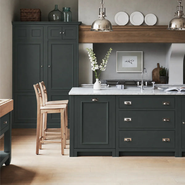 Chichester kitchen with cabinetry painted in Constable Green, featuring a central island and oak bar stools.