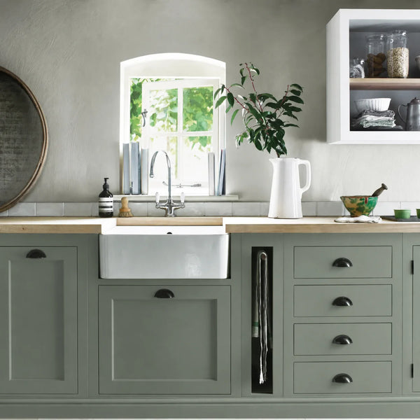 Cactus green painted Henley kitchen cabinetry with oak worktops and a white farmhouse sink.