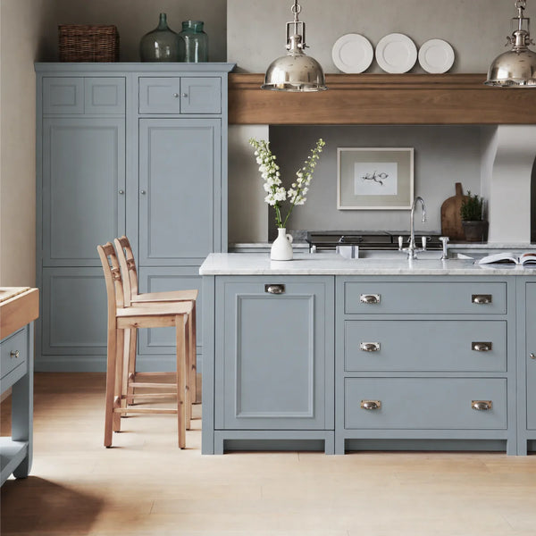 Chichester kitchen with cabinetry painted in Flax Blue, featuring a central island and oak bar stools.
