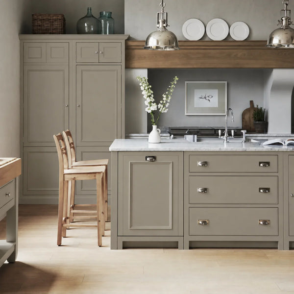 Chichester kitchen with cabinetry painted in Honed Slate beige grey, featuring a central island and oak bar stools.