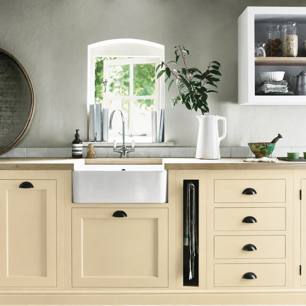 Polenta butter yellow painted Henley kitchen cabinetry with oak worktops and a white farmhouse sink.