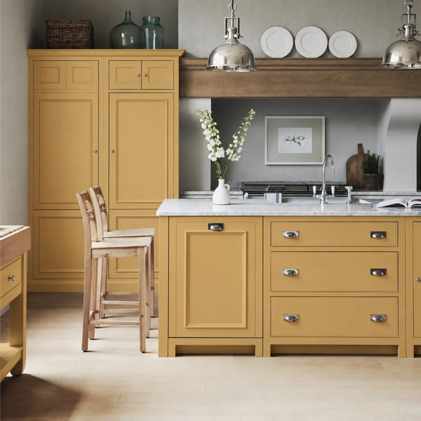 Chichester kitchen with cabinetry painted in Saffron yellow, featuring a central island and oak bar stools.