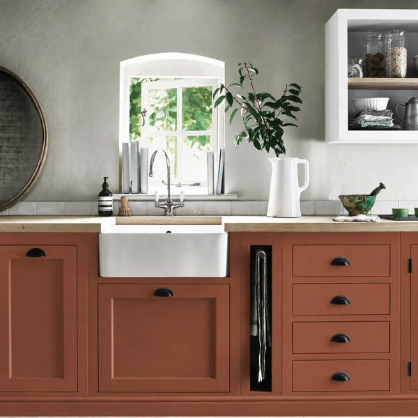 Chestnut burnt orange painted Henley kitchen cabinetry with oak worktops and a white farmhouse sink.