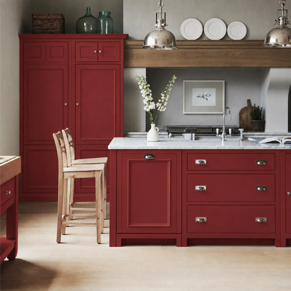 Chichester kitchen with cabinetry painted in Burnham Red, featuring a central island and oak bar stools.