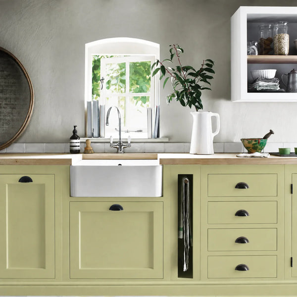 Quince green painted Henley kitchen cabinetry with oak worktops and a white farmhouse sink.