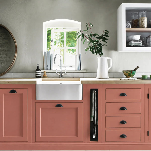 Rhubarb pink painted Henley kitchen cabinetry with oak worktops and a white farmhouse sink.