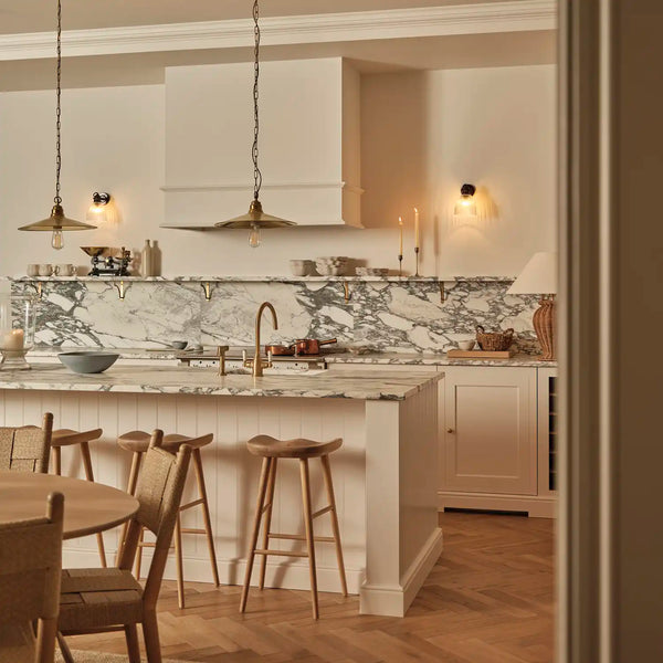 Grand Henley kitchen with Lead light brown painted cabinetry, marble splashback and shelves, with a marble worktop island with wooden bar stools.