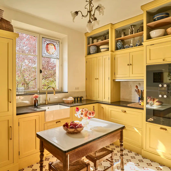 Traditional Henley kitchen with warm Saffron Yellow painted cabinetry, farmhouse sink, granite worktops and freestanding wooden table.