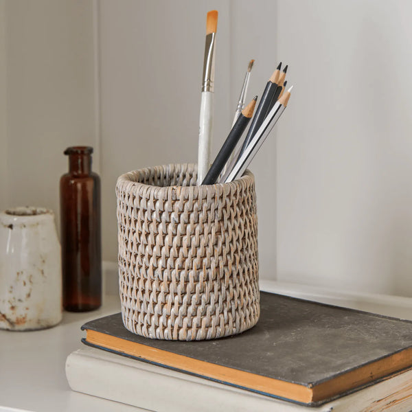 A small cylindrical woven round pen pot made from natural light brown wicker