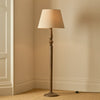 Chalford darkened oak floor lamp with linen shade in a carpeted room with beige walls, light on