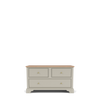 A classic four-drawer chest of drawers in a warm grayish-beige finish with a natural light wood top and small brass knobs, shown on a clean white background.