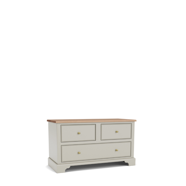 A three-drawer chest of drawers in a warm light gray finish with a natural wood top and small brass knobs, shown on a clean white background.