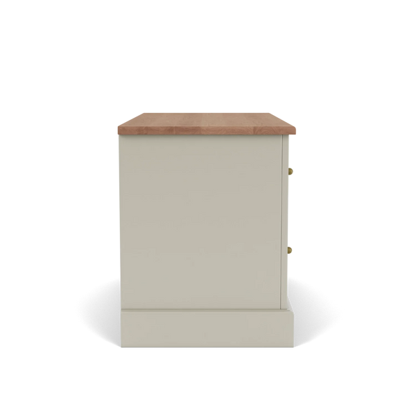 A side view of a small cabinet or nightstand with a warm beige-painted body, a natural wood top, and two small brass knobs, shown on a white background.