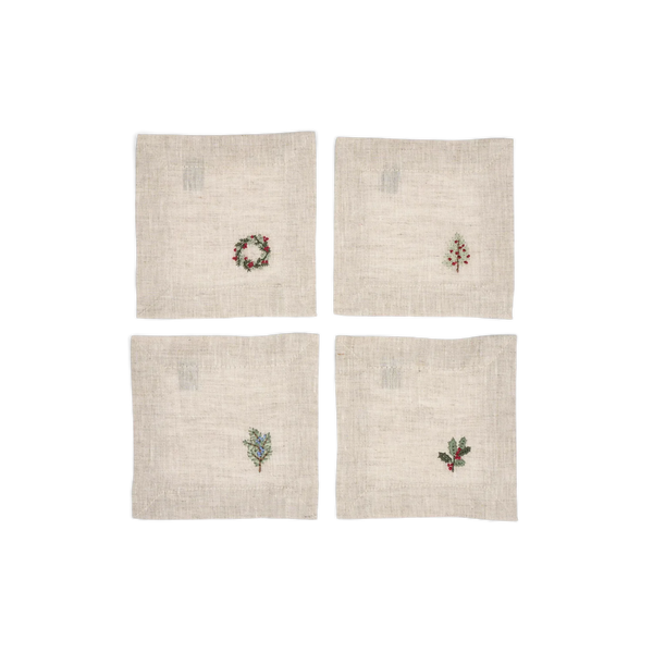 Four square off-white linen napkins arranged in a 2x2 grid on a white background, each featuring a small embroidered holiday motif: a wreath, a Christmas tree, a sprig of mistletoe, and holly with red berries.