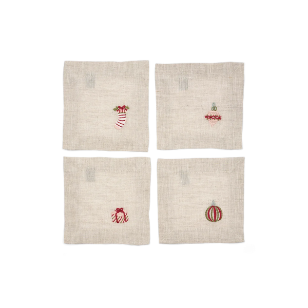 Four square beige linen coasters arranged in a 2x2 grid on a white background, each embroidered with a small Christmas motif including a stocking, ornament, gift box, and bauble.