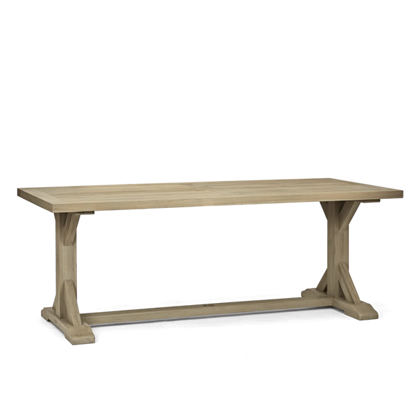 A rustic light oak dining table with a thick rectangular top and trestle-style legs, shown from a three-quarter angle on a white background.