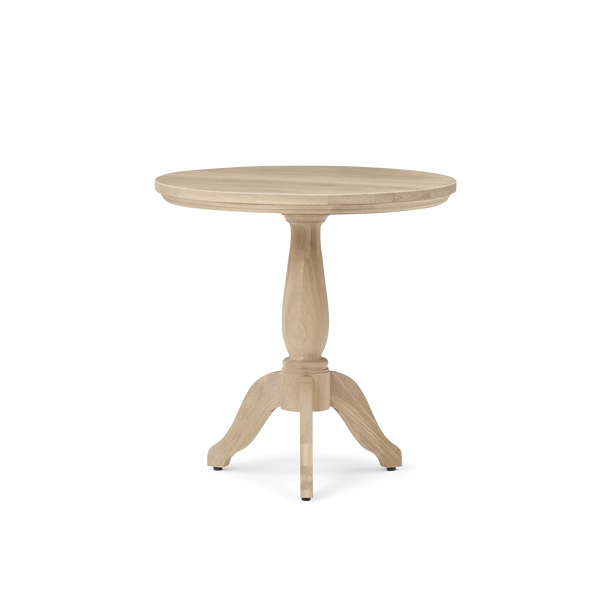 A round pedestal table made of light natural wood, featuring a smooth circular tabletop and three turned legs with small black feet, shown against a plain white background.