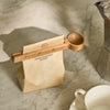 Orford wooden coffee scoop with roasted coffee bag on marble counter next to mug and coffee pot