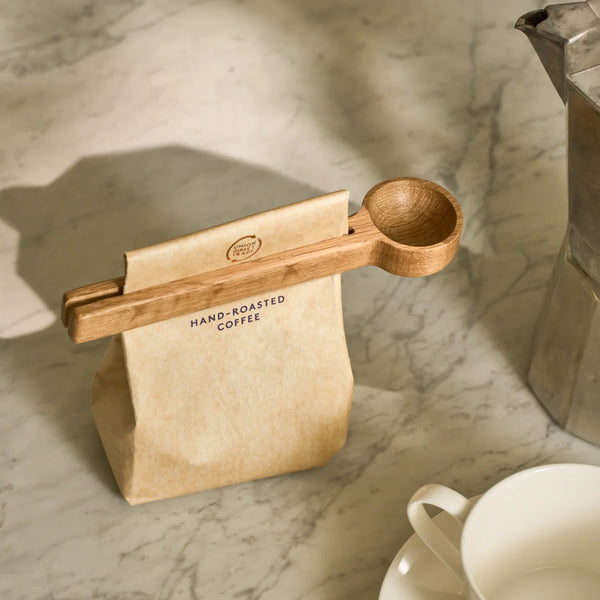 Orford wooden coffee scoop with roasted coffee bag on marble counter next to mug and coffee pot