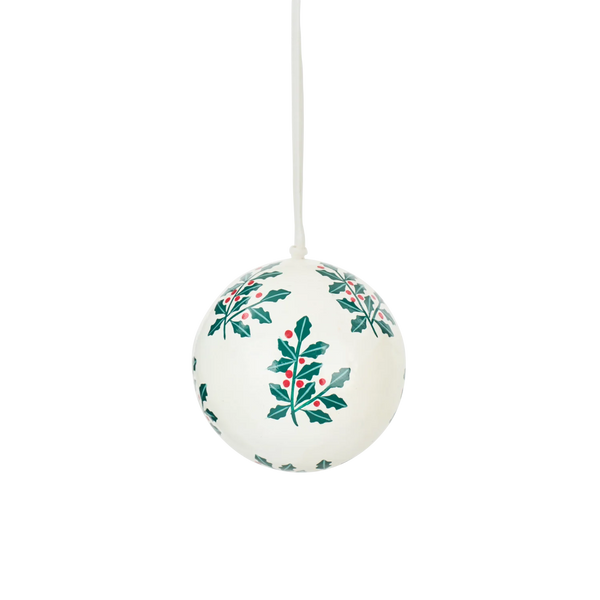A white Christmas ornament ball with a hanging loop, decorated with green holly leaves and small red berries, shown against a plain white background.