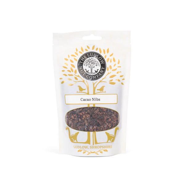 A stand-up pouch of 'The Ludlow Candy Company' Cacao Nibs, featuring a white background with gold tree graphics and a clear window showing the dark brown cacao nibs inside.