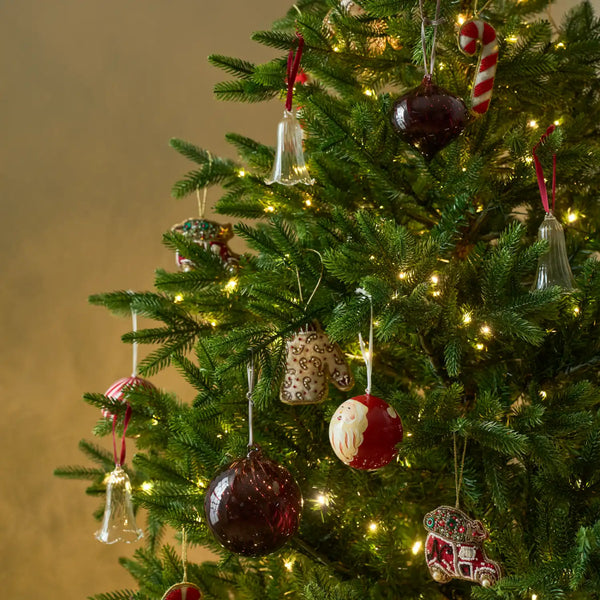A decorated Christmas tree with warm white string lights and assorted ornaments, including red and white candy cane and ball ornaments, against a soft beige background.