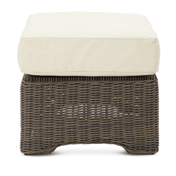 A square outdoor ottoman with a dark brown woven wicker base and a thick, square cream-colored cushion on top, shown against a plain white background.