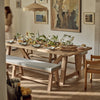 Dining room with a wooden table set for a meal, featuring a bench and chairs.