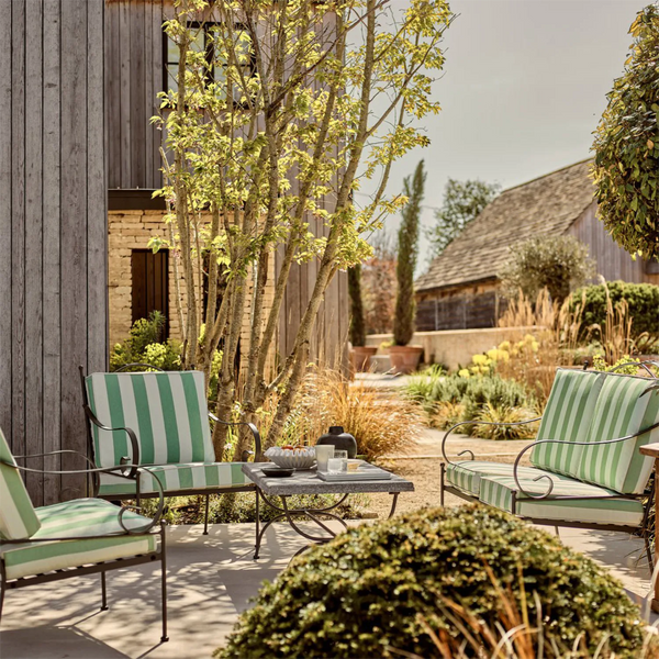 Outdoor patio with green and white striped chairs and a small table.