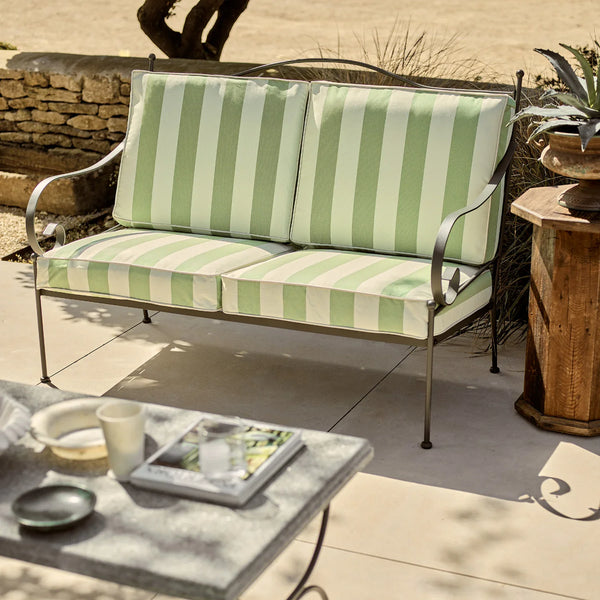Outdoor patio set with green and white striped cushions on a metal frame.