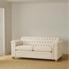 Cream button back Chesterfield style sofa with rolled arms in a room with beige walls and neutral carpet.