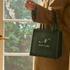 Person holding a green tote bag with 'NEPTUNE' branding in front of a window.