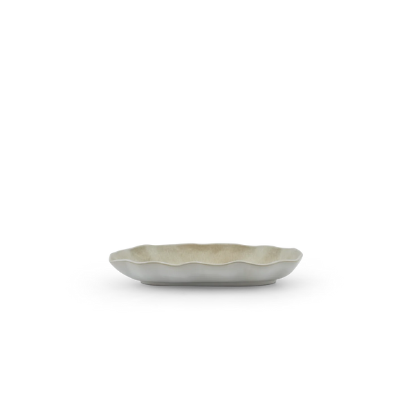 A small scalloped ceramic dish with a matte gray exterior and a warm beige interior, shown on a clean white background.