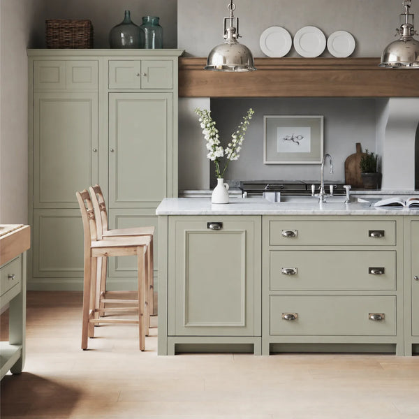 Chichester kitchen with cabinetry painted in Sage Green, featuring a central island and oak bar stools.