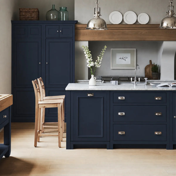 Chichester kitchen with cabinetry painted in Navy Blue, featuring a central island and oak bar stools.