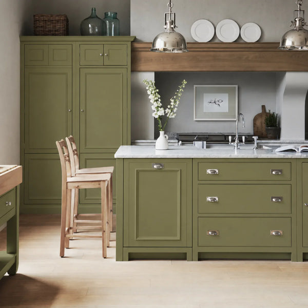 Chichester kitchen with cabinetry painted in Olive Green, featuring a central island and oak bar stools.