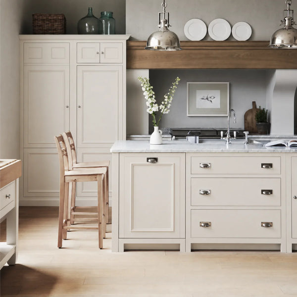 Chichester kitchen with cabinetry painted in Shell White, featuring a central island and oak bar stools.