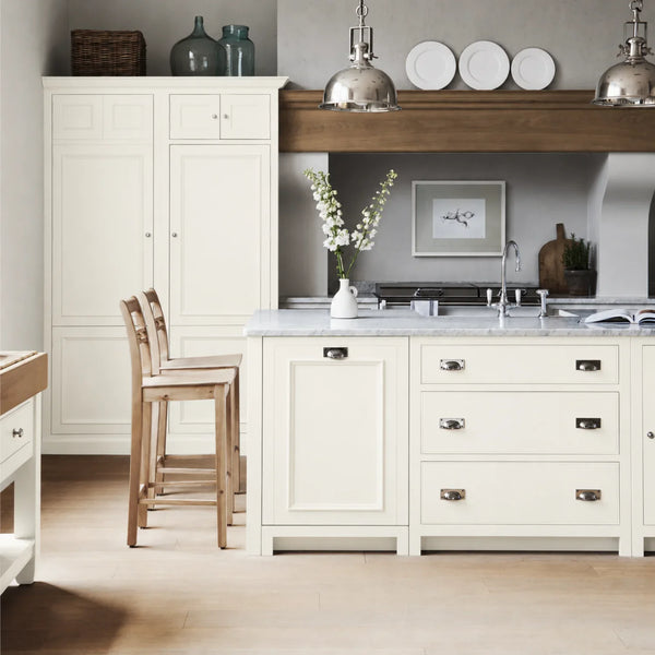 Chichester kitchen with cabinetry painted in Snow white, featuring a central island and oak bar stools.