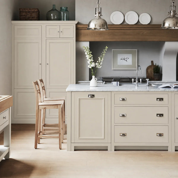 Chichester kitchen with cabinetry painted in Silvery Birch neutral cream, featuring a central island and oak bar stools.