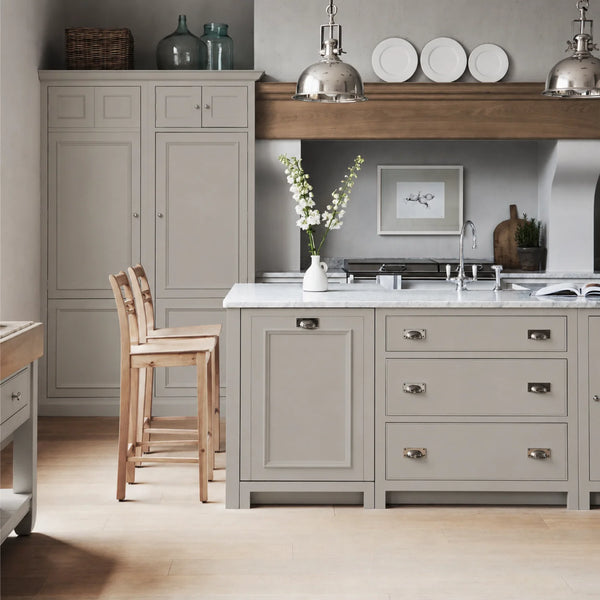 Chichester kitchen with cabinetry painted in Mist beige grey, featuring a central island and oak bar stools.