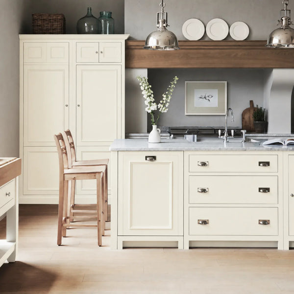 Chichester kitchen with cabinetry painted in Orkney White, featuring a central island and oak bar stools.