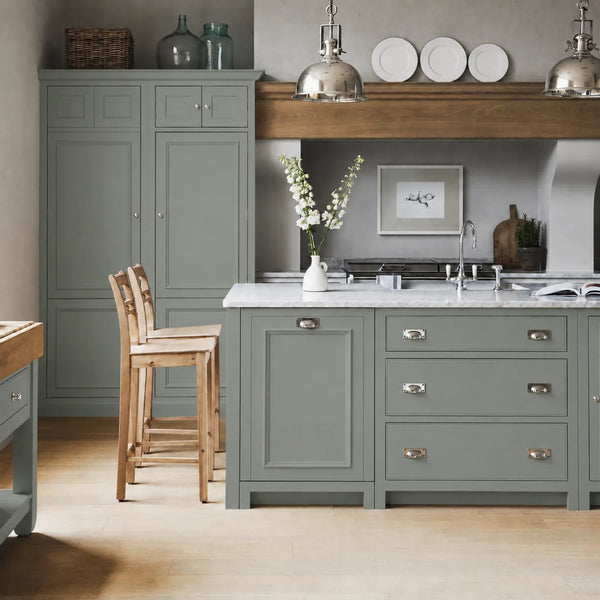 Chichester kitchen with cabinetry painted in Moss Green, featuring a central island and oak bar stools.