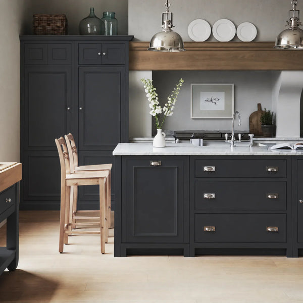 Chichester kitchen with cabinetry painted in Ink navy blue, featuring a central island and oak bar stools.