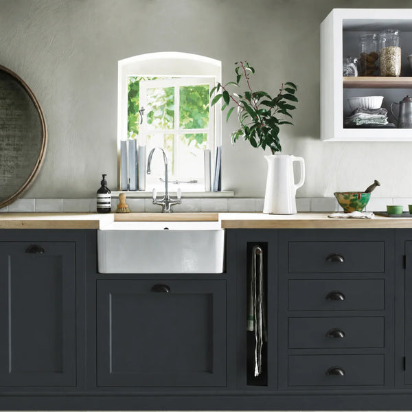 Ink navy blue painted Henley kitchen cabinetry with oak worktops and a white farmhouse sink.