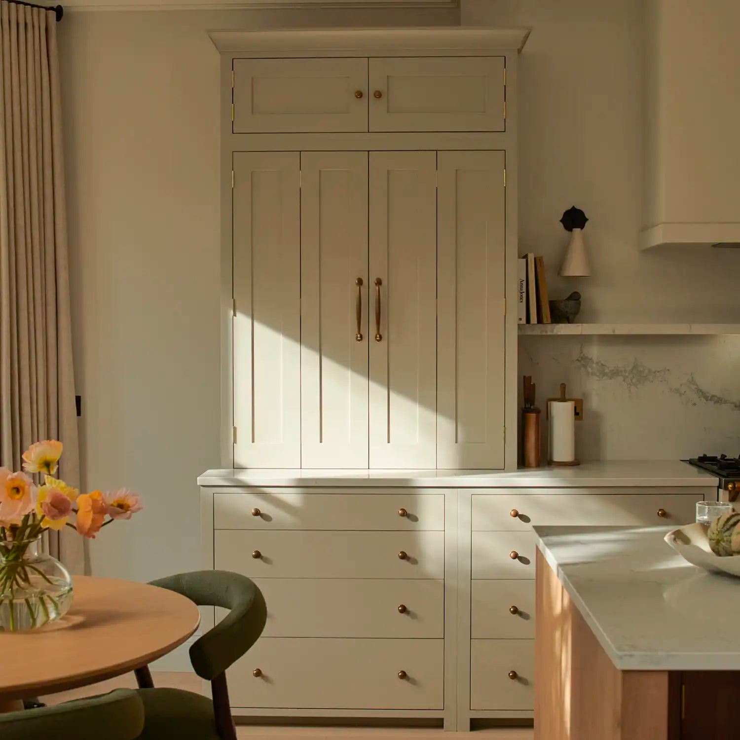 Neutral Orkney White Suffolk Shaker kitchen with tall larder cabinetry, brass hardware and marble-topped oak island.
