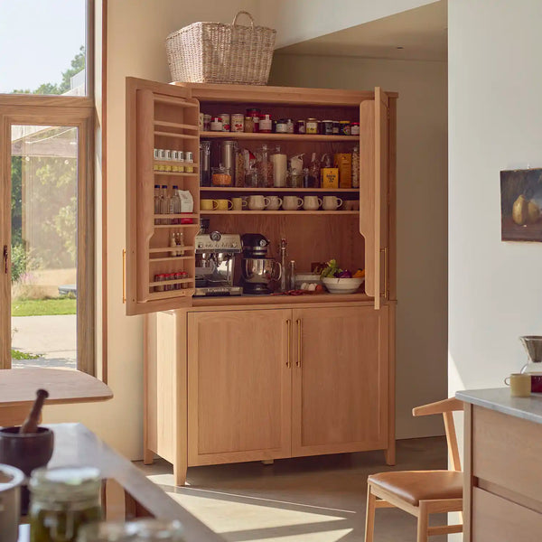 Freestanding Borough oak larder with open doors, internal shelving and small kitchen appliances.